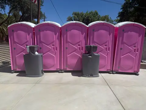 Row of pink event porta potties with two hand wash stations in front