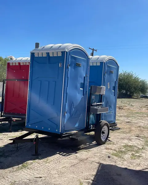 Blue porta potties strapped on a delivery trailer