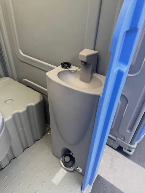 Roomy porta potty interior with a molded hand sanitizer stand beside the seat