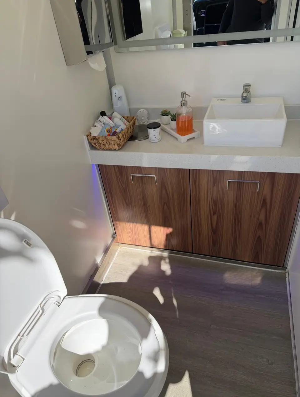 Restroom trailer interior with vessel sink, wood vanity and mirror