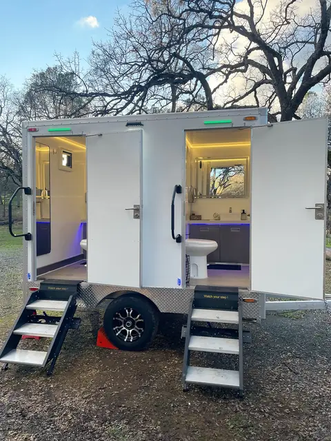 Two-stall restroom trailer with lit interiors and fold-down steps