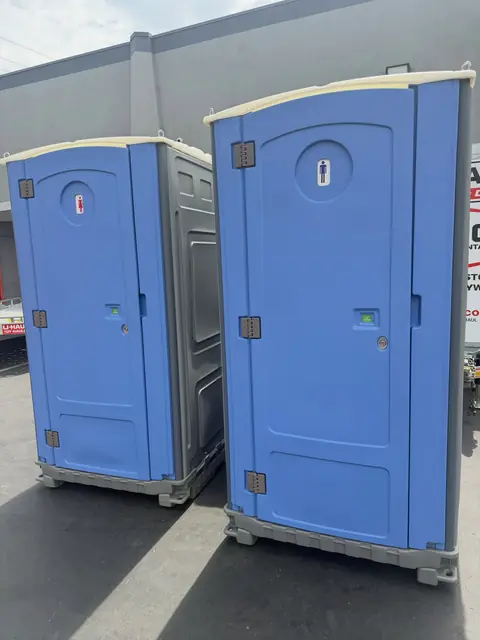 Two blue standard porta potties side by side on pavement